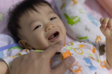 Baba eliyle bebek ağzını kontrol ediyor.