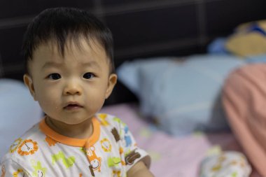 Yatakta yatan 1 yaşındaki bir çocuğun portresi..