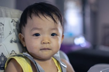 Bebek koltuğunda oturan sevimli, mutlu Asyalı bir Çinli bebeğin portresi.