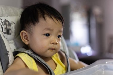 Bebek koltuğunda oturan sevimli, mutlu Asyalı bir Çinli bebeğin portresi.