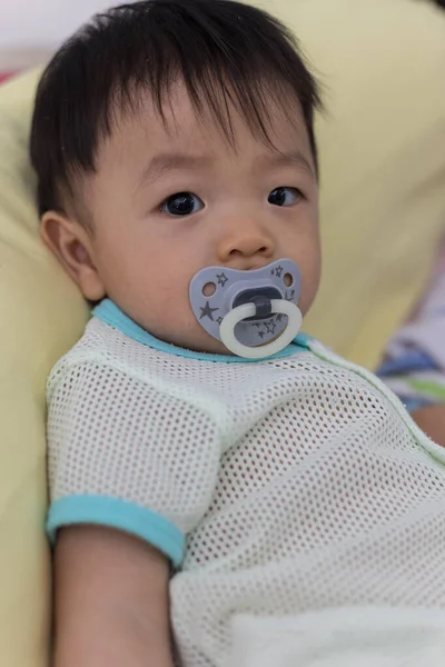 Yatağında emzik emziren tatlı bir erkek bebeğin portresi.