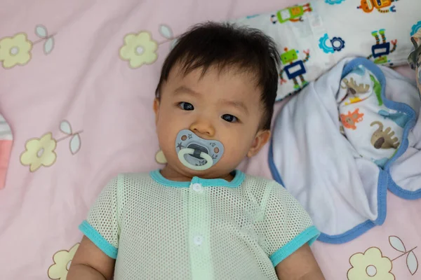 Yatağında emzik emziren tatlı bir erkek bebeğin portresi.