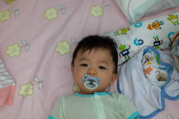 Yatağında emzik emziren tatlı bir erkek bebeğin portresi.