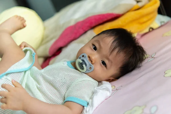 Yatağında emzik emziren tatlı bir erkek bebeğin portresi.