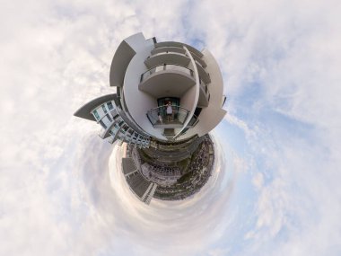 Küçük gezegen efektleri modern mimariyi gözler önüne seriyor, bir çift balkonda, ve bulutlu bir gökyüzü.