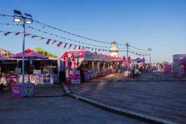 Zhuhai, Guangdong, Çin - 14 Mayıs 2025: İnsanlar masalarında oturup Çin 'deki hareketli bir gece pazarındaki renkli gıda tezgahlarından yerel lezzetlerin tadını çıkarıyorlar