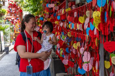 Geleneksel Çin tapınağında kalp şeklinde dilek kartlarına bakan bir turist ailesi.