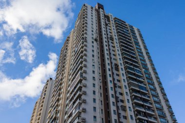 Beyaz bulutlu mavi gökyüzüne karşı yükselen yerleşik gökdelenler modern şehir yaşamını gözler önüne seriyor..