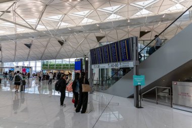 Hong Kong, Çin - 16 Mayıs 2025: Hong Kong Uluslararası Havaalanı 'na varış ve kalkış panosuna bakan turistler