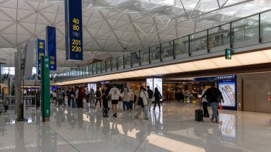 Hong Kong, Çin - 16 Mayıs 2025: Hong Kong Uluslararası Havaalanı 'ndaki kalkış salonunda bavullu turist grubu