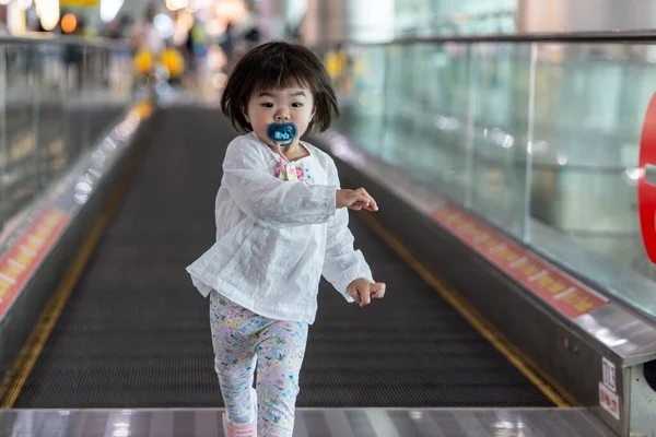 Yeni yürümeye başlayan çocuk havaalanında yürürken eğleniyor.