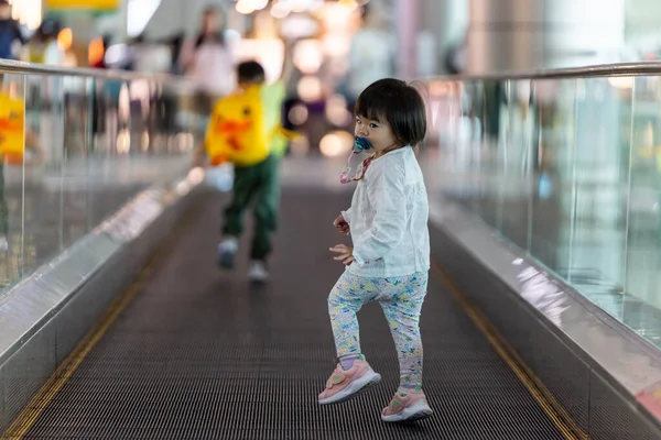 Yeni yürümeye başlayan çocuk havaalanında yürürken eğleniyor.