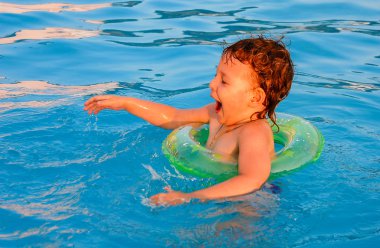 Küçük kız havuzda yüzüyor.