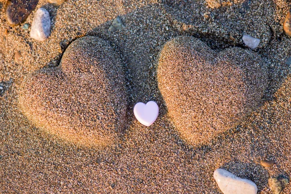 Duas formas de coração de areia na areia junto ao mar — Fotografia de Stock