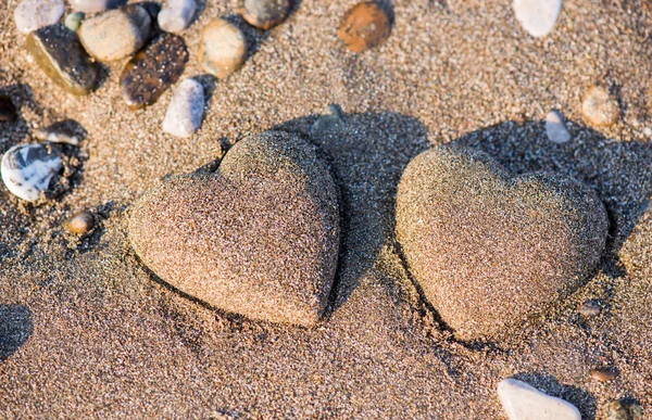 Dos arenas en forma de corazón en la arena junto al mar Imagen de archivo