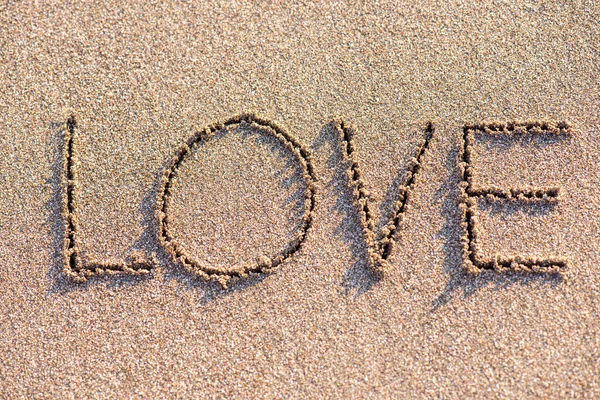 砂の背景に単語「愛」 — ストック写真