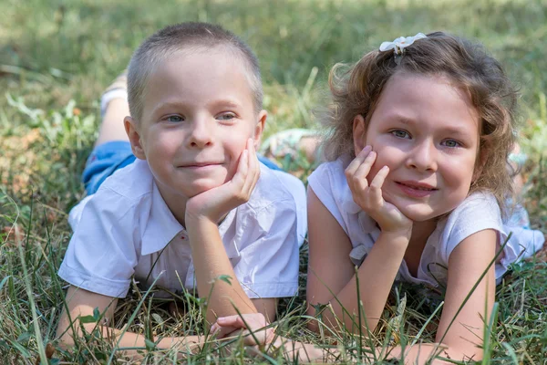 Menino e a menina jazem juntos em uma grama — Fotografia de Stock