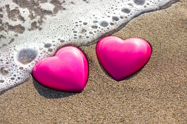 Två röda hjärtan på stranden symboliserar kärlek — Stockfoto