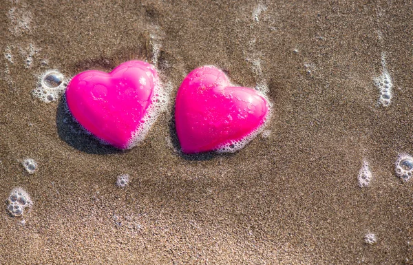 Twee rode harten op het strand symboliseert liefde — Stockfoto