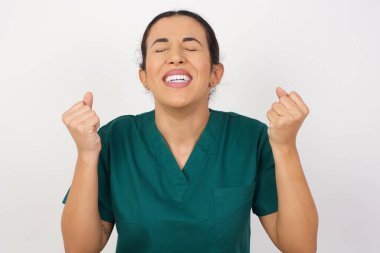 Güzel genç hemşire, zafer kutlamaları için kollarını kaldırarak ve gözlerini kapayarak başarıya ulaşmak için heyecanlanıyor. Kazanan konsept.