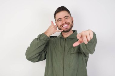 Model neşeli bir şekilde gülümsüyor ve kamerayı işaret ederek seni daha sonra arıyor, telefonla konuşuyor. 