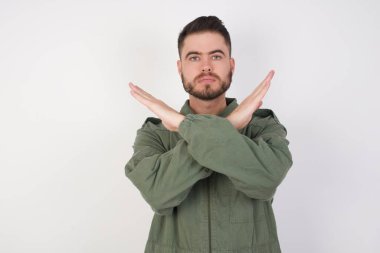 Reddedilmiş genç beyaz adam kollarını kavuşturup negatif işaret veriyor, kızgın surat.