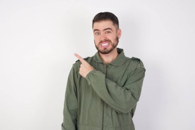 Genç yakışıklı adam endişeli ve gergin bir kenara işaret ediyor. İşaret parmağı, endişe ve sürpriz konseptiyle..