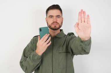 Stüdyonun arka planında akıllı telefonlu çekici bir genç adamın fotoğrafı.