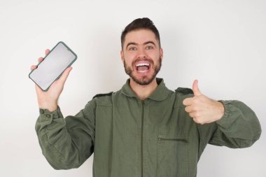 Stüdyonun arka planında akıllı telefonlu çekici bir genç adamın fotoğrafı.