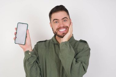 Stüdyonun arka planında akıllı telefonlu çekici bir genç adamın fotoğrafı.