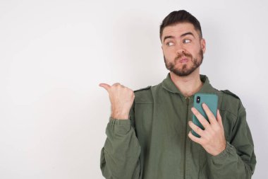 Stüdyonun arka planında akıllı telefonlu çekici bir genç adamın fotoğrafı.