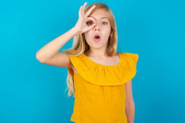 Küçük kız iyi bir hareket yapıyor. Şaşırmış bir yüz, parmaklarının arasından bakan bir göz. İnançsız ifade.