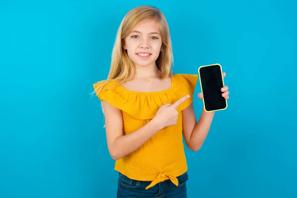 Leende Liten Flicka Pekar Med Pekfingret Mobiltelefon Med Tom Skärm — Stockfoto