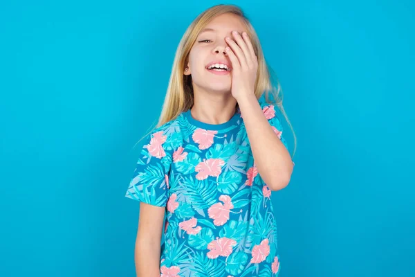 little girl makes face palm and smiles broadly, giggles positively hears funny joke poses