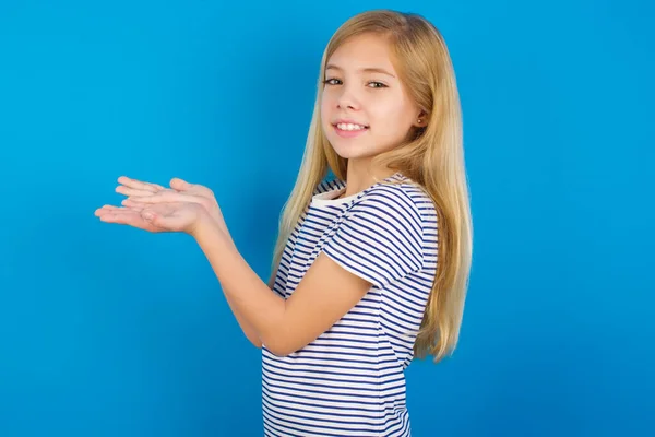 Kaukaska Dziewczyna Noszenie Pasiasty Koszula Przeciw Niebieski Ściana Wskazując Bok — Zdjęcie stockowe