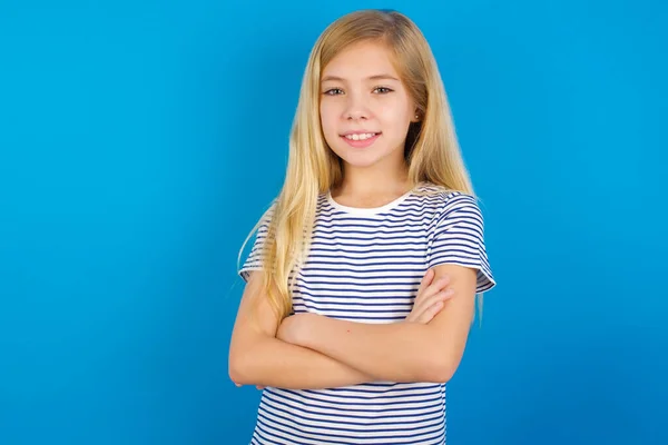 Biała Dziewczyna Pasiastej Koszuli Niebieskiej Ścianie Uśmiechnięta Skrzyżowanymi Ramionami Patrząca — Zdjęcie stockowe