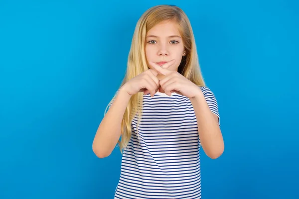 青い壁に縞模様のシャツを着た白人の少女 否定的な記号を行う指を横断拒絶怒りの表現を持っている — ストック写真