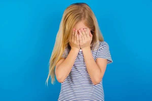 顔を手で覆っている青い壁に縞模様のシャツを着た白人の少女は 荒廃して泣いています 悲しい概念 — ストック写真