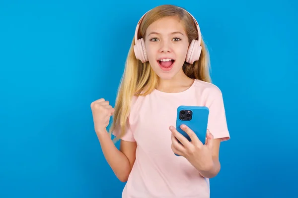 Positief Blank Meisje Draagt Roze Shirt Tegen Blauwe Muur Houdt — Stockfoto