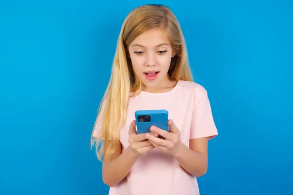 Menina Caucasiana Vestindo Camiseta Rosa Contra Parede Azul Usando Telefone — Fotografia de Stock