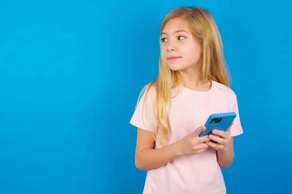 Blank Kind Meisje Dragen Roze Shirt Tegen Blauwe Muur Houdt — Stockfoto