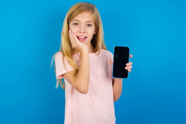 Menina Criança Caucasiana Vestindo Camisa Rosa Contra Parede Azul Segurar — Fotografia de Stock