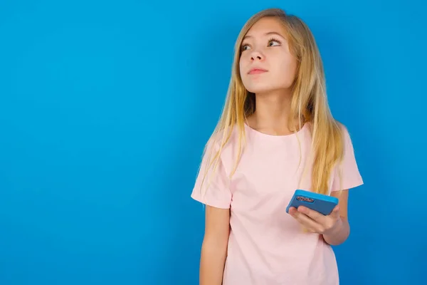 Garota Caucasiana Vestindo Camisa Rosa Contra Parede Azul Detém Telefone — Fotografia de Stock