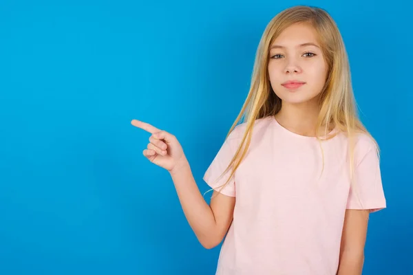 Blanke Meisje Draagt Roze Shirt Tegen Blauwe Muur Wijst Naar — Stockfoto