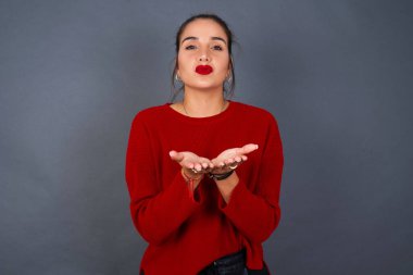 Genç İspanyol kadın öpücük yolluyor dudaklarıyla ve avuç içleriyle hava öpücüğü yolluyor..