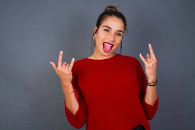 Genç İspanyol kadın taş el hareketi yapıyor ve dil gösteriyor.