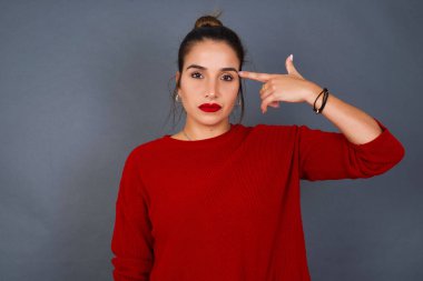 Mutsuz genç İspanyol kadın intihar jesti yapıyor ve tabancayı eliyle taklit ediyor, kıvrımlı dudaklar iki parmağını şakakta tutuyor, ateş ediyor, her şeyden bıkıyor.,