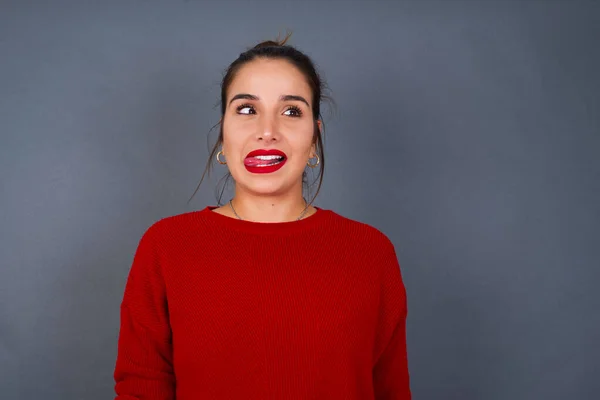 young Hispanic woman showing grimace face crossing eyes and showing tongue. Being funny and crazy