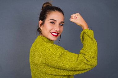 Yakın plan profil portresi. Güçlü, neşeli, İspanyol bir kadının pembe pastel arka planda izole edilmiş kaslarını gösteriyor.