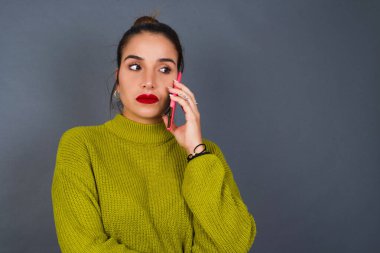 Akıllı telefondan konuşan üzgün, genç bir İspanyol kadın. İletişim konsepti.